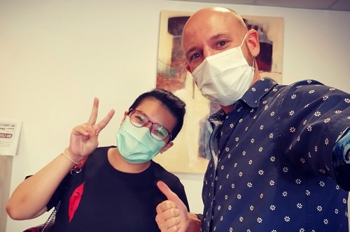 Une adulte et son ostéopathe Arnaud Le Coz se prenant en selfie et portant un masque après une séance d'ostéopathie